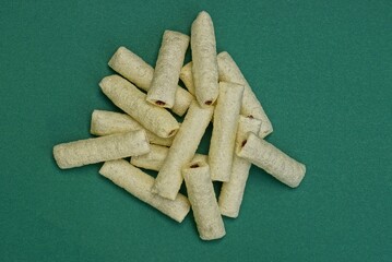 food from white long corn sticks with chocolate filling in a heap lie on a green table