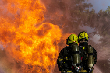 firefighters wearing fire fighter suit for safety and using twirl water extinguisher for fighting the fire flame in emergency situation.. - Safety Firefighter and industrial concept.