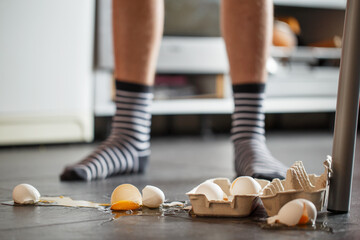 Broken eggs - accident at kitchen, mess. Legs on background - 455732513