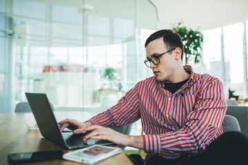 Focused man typing on keyboard of laptop in office