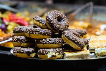 donuts with chocolate icing and nuts stack close-up