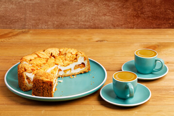 Homemade pie with nectarines and two cups of coffee espresso on wooden table. Copyspace.