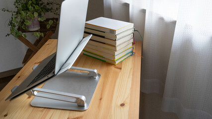 山積みの本とノートブック。PCスタンド。