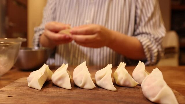 Making pot stickers at home. Mom wrapping meat
