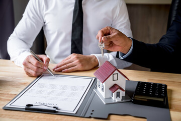 Real estate agent hand over the keys during meeting after signing rental lease contract or sale purchase agreement And congratulate buyers after giving buyers a purchase contract.sign contract concept