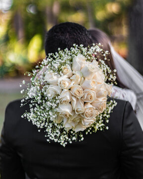 Bride holding a white flower bouquet and kissing the groom