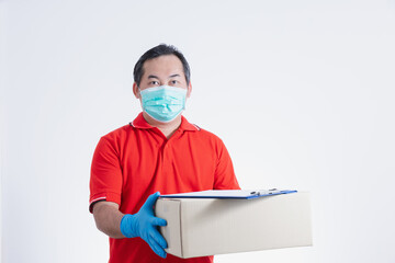 Fototapeta na wymiar Portrait of Asian delivery man with face medical mask in red cloth holding a box package. Isolated on white studio background with copy space. Delivery, Sold out online concept.