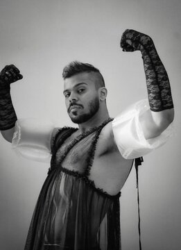 Grayscale photo of a man wearing lingerie and arm floaties indoor