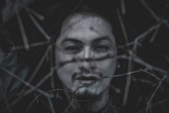 Grayscale portrait of a man between tree branches