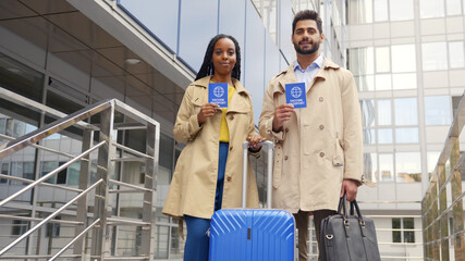 Happy diverse couple tourists looking at camera and showing vaccination passport