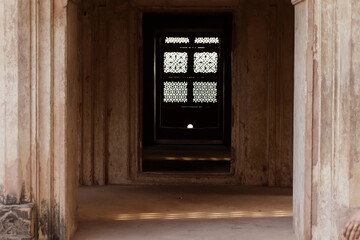 Fototapeta na wymiar A beautifully carved lattice window casting light and shadow in a hall in the ancient Raja Mahal palace.