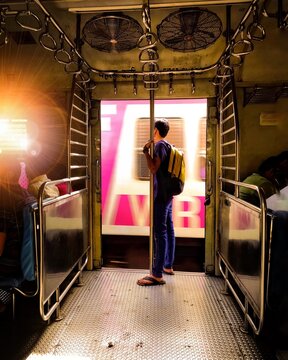 Man standing and leaning on a pole beside the train door