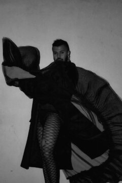Man wearing fishnet panty hose and black dress in grayscale