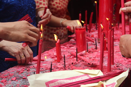 People lighting candles on table for prayer