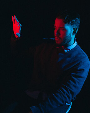Portrait of man wearing sweater and collared shirt in red dim lit room