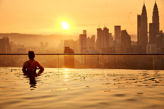 rear view of woman in the infinity pool on rooftop in Kuala Lumpur during sunset
