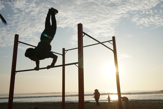 Silhouette of boy playing gymnastics at the beach during sunset