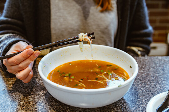 Woman eating miso soup with chopsticks