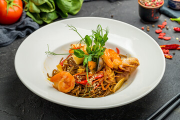 Fried soba noodles with seafood on black stone table