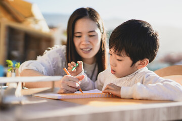 Asian nanny and child doing drawing activities outdoor on patio - Mother and child love - Concept...