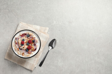 Tasty oatmeal porridge with toppings served on grey table, flat lay. Space for text