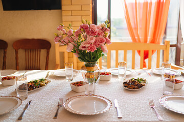 bouquet of pink flowers in a vase on the table served on the terrace. 