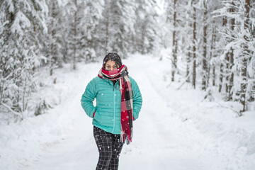 Fototapeta na wymiar Portrait of a beautiful woman dressed with colourful jacket. A beautiful woman in coloured jacket walking through the Magical winter forest.