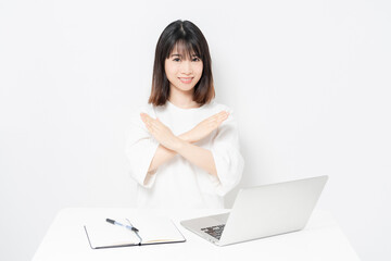 ノートパソコンを使いながらNGサインをする若い女性