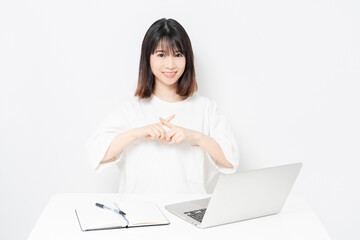 ノートパソコンを使いながらNGサインをする若い女性
