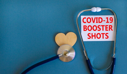 Covid-19 booster shots vaccine symbol. White card with words Covid-19 booster shots, beautiful blue background, wooden heart and stethoscope. Covid-19 booster shots vaccine concept. - obrazy, fototapety, plakaty