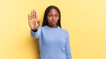 afro black pretty woman looking serious, stern, displeased and angry showing open palm making stop...