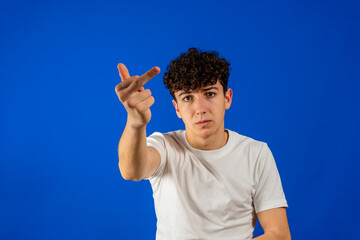 Portrait of a young man showing middle finger gesturing fuck isolated on blue background. Gesture...