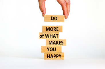 Do what makes you happy symbol. Wooden blocks with words 'Do more of what makes you happy'. Businessman hand. Beautiful white background, copy space. Business, do what makes you happy concept.