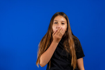 Close-up studio shot of beautiful brunette little girl posing against a blue background.