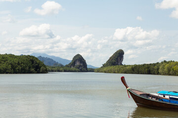 Naklejka na ściany i meble boat part on the background river wide among rocks covered tropical jungle