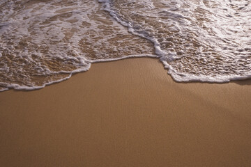 White boiling foam surf on the tropical sandy beach with copy space