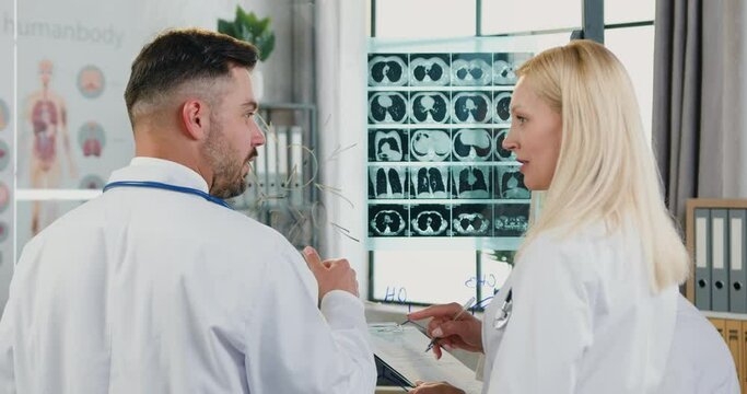 Workflow in hospital where attractive confident qualified smart diverse doctors discussing results of patient's x-ray scan and concept of further treatment