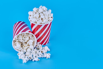 Two glasses of popcorn stand on a blue background