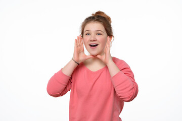 Attention, Good News. Beautiful young girl holding arms near open mouth and screaming, dressed in pink casual sweatshirt