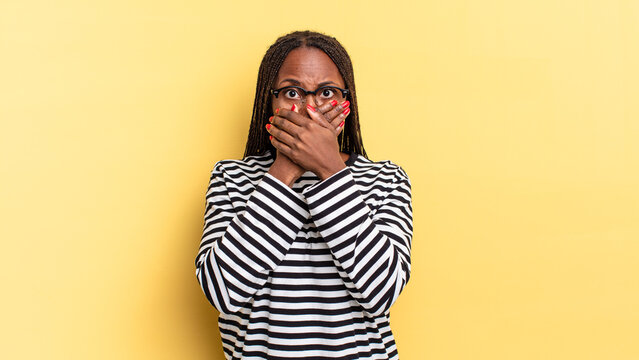 afro black pretty woman covering mouth with hands with a shocked, surprised expression, keeping a secret or saying oops
