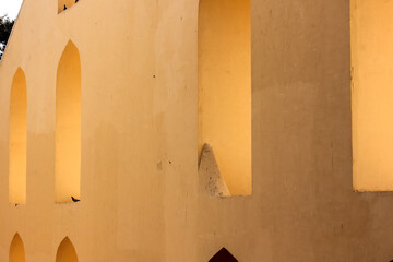 The exterior facade with arched windows of the ancient astronomical observatory of Jantar Mantar in the city of Jaipur in Rajasthan, India.