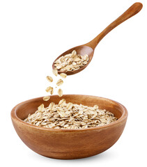 Oatmeal pours out of a spoon into a plate on a white background. Isolated