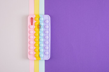 colorful bright case for a smartphone in the form of a trendy trendy antistress toy pop it on a multicolored background