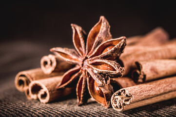 Christmas baking spices, cinnamon sticks and anise stars for Christmas cake, cookies or mulled wine on a black background, macro photo