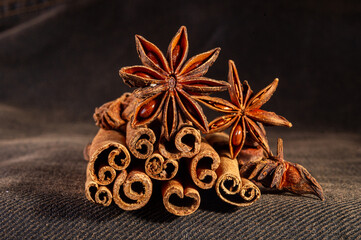 Christmas baking spices, cinnamon sticks and anise stars for Christmas cake, cookies or mulled wine on a black background, macro photo