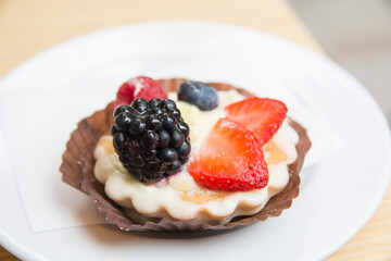 Fruit tartlet, containing strawberries and blackberries and raspberries, served on a plate