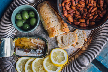 tinned fish sardines snack platter silver tray with almonds, bread, green olives, lemon slices 