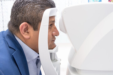 Latino adult with vision problems undergoes an eye exam to evaluate the effects on his cornea.