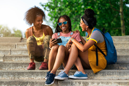Three African teenage girls using a smartphones - Powered by Adobe