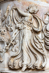 lose-up on decorative sculptures engraved on a marble wall representing a young woman in a beautiful dress dancing